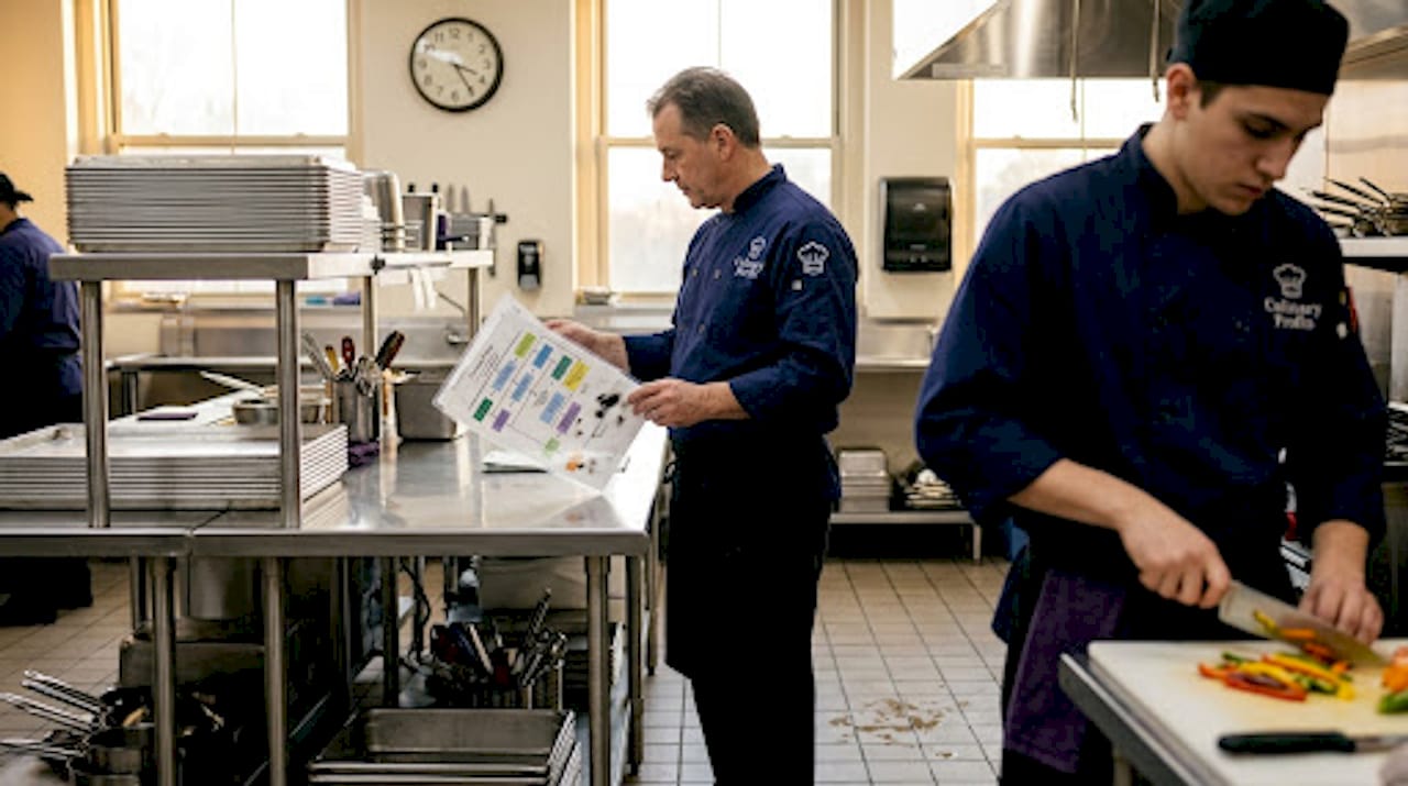 Kitchen manager reviewing operations in large kitchen