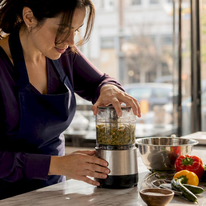 Woman using small food processor in home kitchen
