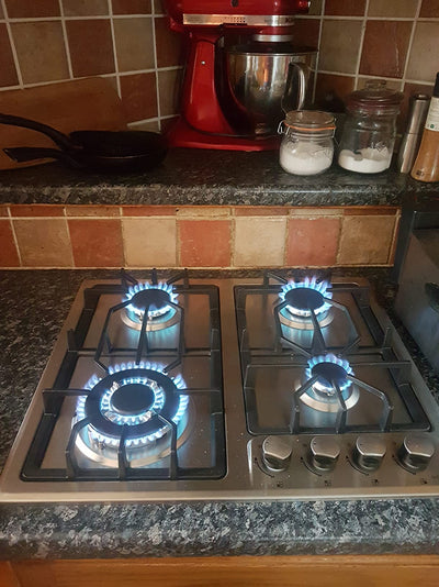 Gas stove with lit burners on a kitchen counter, featuring a red stand mixer and jars in the background.
