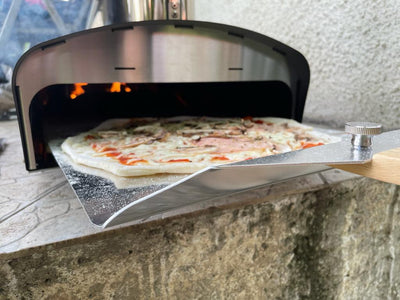 Outdoor pizza oven with a pizza being cooked on a stone surface
